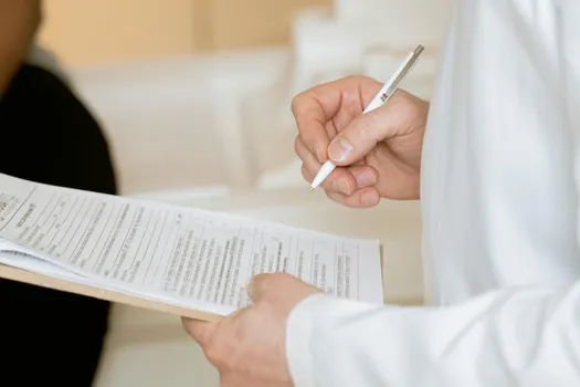 A doctor reviewing a report, holding a pen in hand.